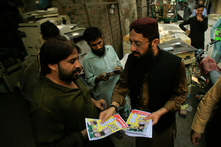 Mohammad Yaqoob Sheikh (R) nominated candidate of political party, Milli Muslim League (MML), distributes handbills to residents during an election campaign for the National Assembly NA-120 constituency in Lahore, Pakistan September 10, 2017. Picture taken September 10, 2017. REUTERS/Mohsin Raza