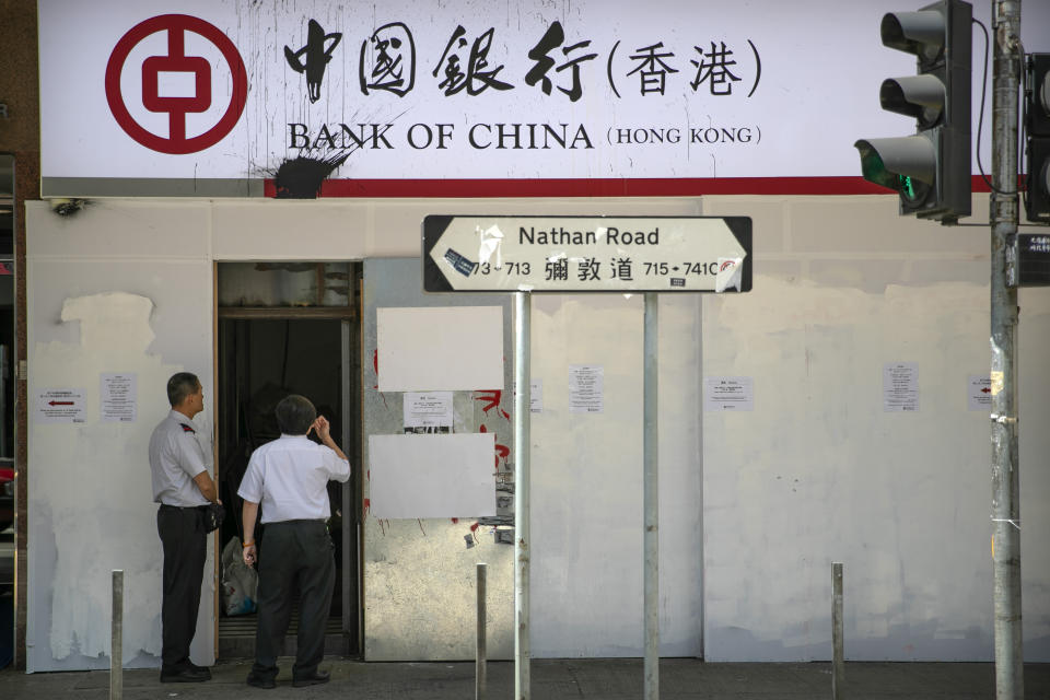 Security guards stand outside the entrance of a Bank of China branch that has been covered in barriers in Hong Kong, Friday, Oct. 25, 2019. Banks, retailers, restaurants and travel agents in Hong Kong with ties to mainland China or perceived pro-Beijing ownership have fortified their facades over apparent concern about further damage after protesters trashed numerous businesses following a recent pro-democracy rally. (AP Photo/Mark Schiefelbein)