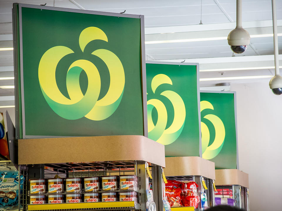 Woolworths logo signs above supermarket shelves