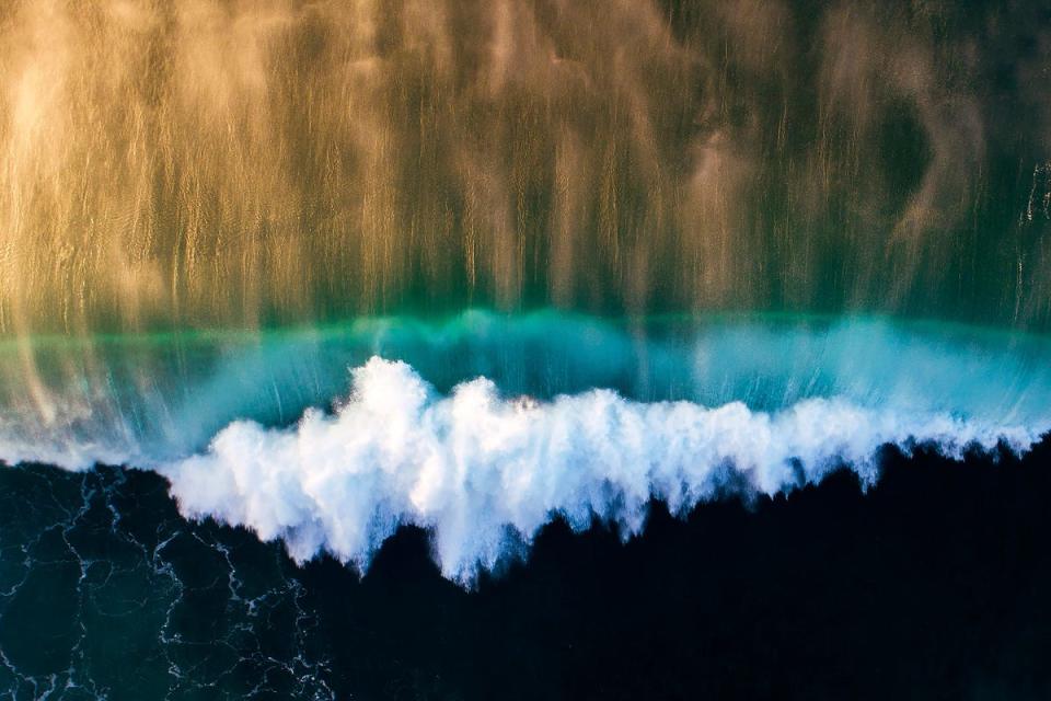 Hit by the colors of a setting sun, one of the most famous waves on the North Shore, Pipeline, is captured from above in "Golden Pipe."