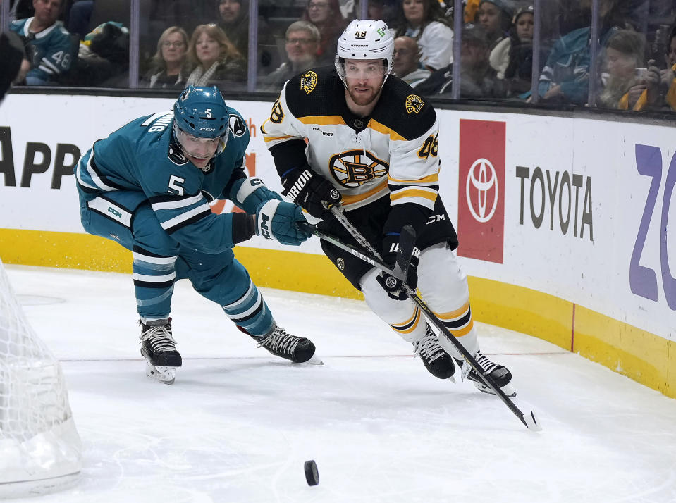 San Jose Sharks defenseman Matt Benning (5) and Boston Bruins defenseman Matt Grzelcyk (48) vie for the puck during the first period of an NHL hockey game Saturday, Jan. 7, 2023, in San Jose, Calif. (AP Photo/Tony Avelar)