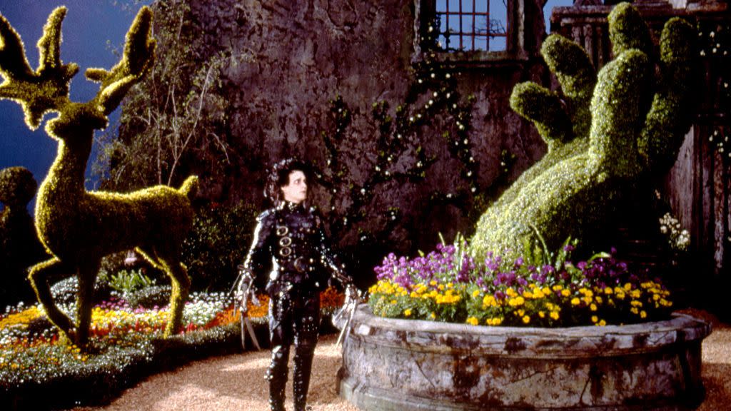 edward stands in front of a sculpted bush in a scene from edward scissorhands a good housekeeping pick for best halloween movies