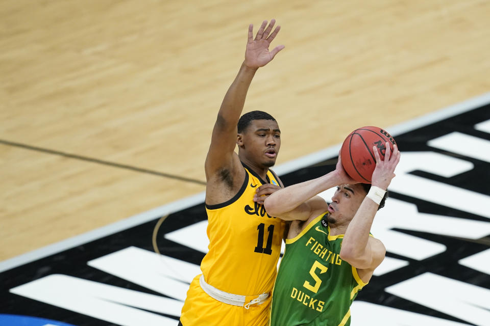 Oregon's Chris Duarte (5) is fouled by Iowa's Tony Perkins (11) as he goes up for a shot during the first half of a second-round game in the NCAA men's college basketball tournament at Bankers Life Fieldhouse, Monday, March 22, 2021, in Indianapolis. (AP Photo/Darron Cummings)