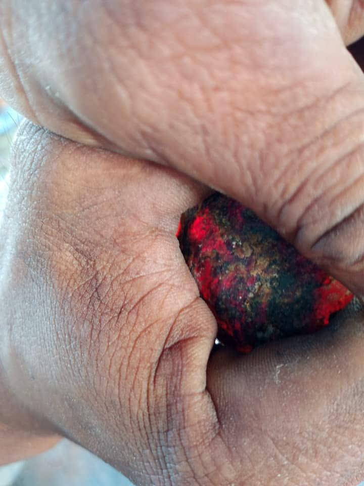 Woman holds glowing red rock. 