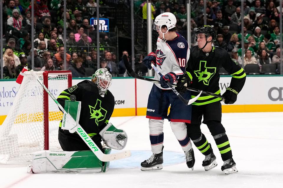Dallas Stars goaltender Jake Oettinger (29) uses his right arm pad to block a shot as Columbus Blue Jackets left wing Dmitri Voronkov (10) and defenseman Nils Lundkvist, right, looks on in the second period of an NHL hockey game, Monday, Oct. 30, 2023, in Dallas. (AP Photo/Tony Gutierrez)