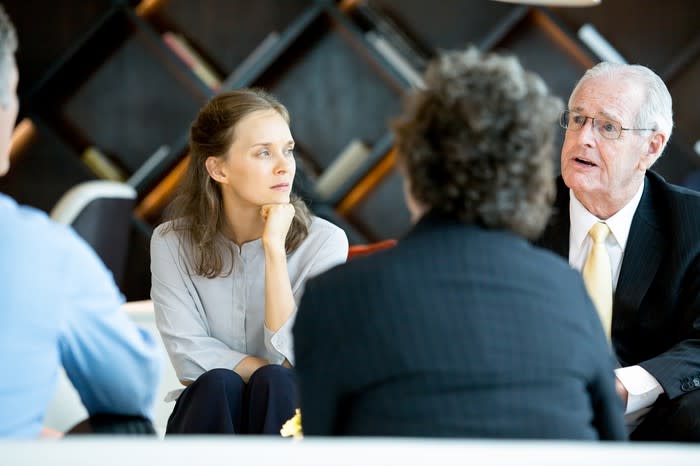 Older man sitting with his family and having a serious discussion.