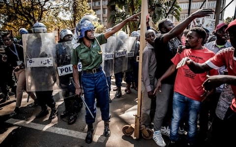 Zimbabwean anti riot police officers close the entrance to the Rainbow Towers where the election's results were announced - Credit: AFP
