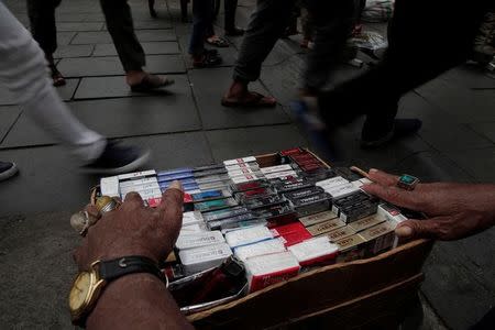 A street vendor selling cigarettes waits for customers on a street in Jakarta, Indonesia, May 10, 2017. REUTERS/Beawiharta/Files