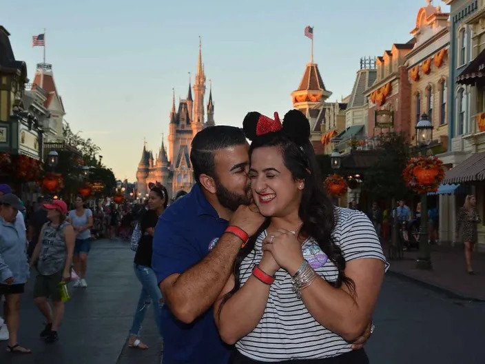 stephanie and her husband posing on main street at magic kingdom