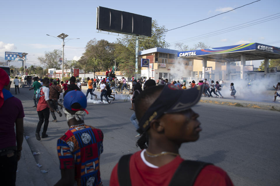 Factory workers demanding a salary increase run for cover as police launch tear gas to disperse them, in Port-au-Prince, Haiti, Thursday, Feb. 10, 2022. The workers employed at factories that produce textiles and other goods say they make 500 gourdes ($5) a day for nine hours of work and are seeking a minimum of 1,500 gourdes ($15) a day. (AP Photo/Odelyn Joseph)