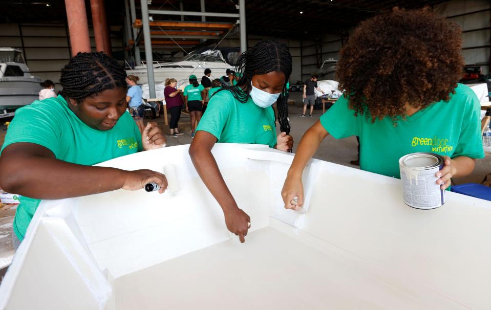 Jewell Marsh, 15, of Ferndale, left, Kayden Smith, 15, of Southfield, and McKenzi McGill, 18, of Lansing, paint their 12-foot Bevin's Skiff at Riverside Marina in Detroit on Aug. 10, 2022. Adams and other teenagers from metro Detroit participated in the weeklong Detroit River Skiff and Schooner program through the University of Michigan's Detroit River Story Lab.