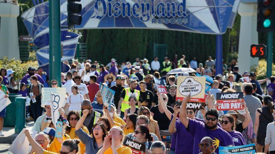 Hundreds of Disneyland workers are seen with signs protesting outside the park's gates 