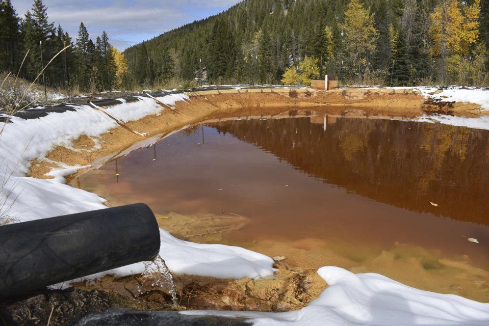 In this Oct. 12, 2018 photo, water contaminated with arsenic, lead and zinc flows from a pipe out of the Lee Mountain mine and into a holding pond near Rimini, Mont. The community is part of the Upper Tenmile Creek Superfund site, where dozens of abandoned mines have left water supplies polluted and residents must use bottled water. (AP Photo/Matthew Brown)