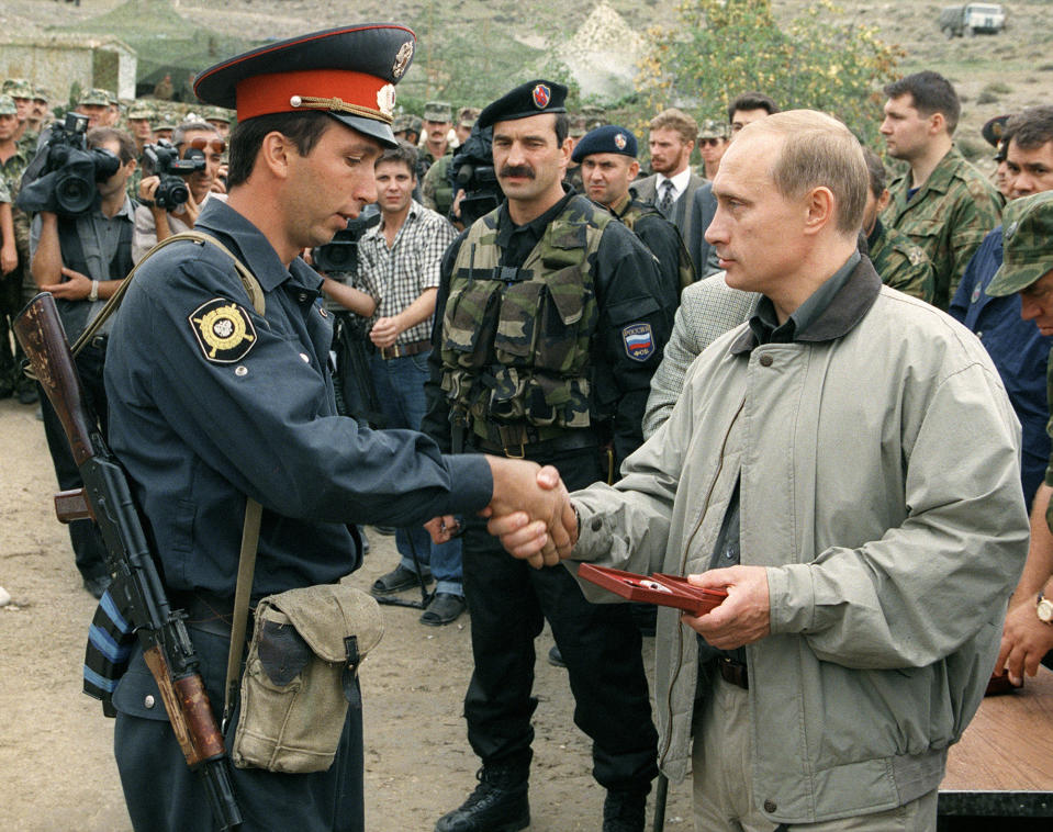 FILE - Vladimir Putin, right, presents an award to a police officer at a military base in the mountains in the Dagestan region of Russia on Aug. 27, 1999. Former President Boris Yeltsin named the relatively little-known Putin as his prime minister, on Aug. 9, 1999, and Putin has led the country in that post and as president for nearly a quarter century. (AP Photo, File)