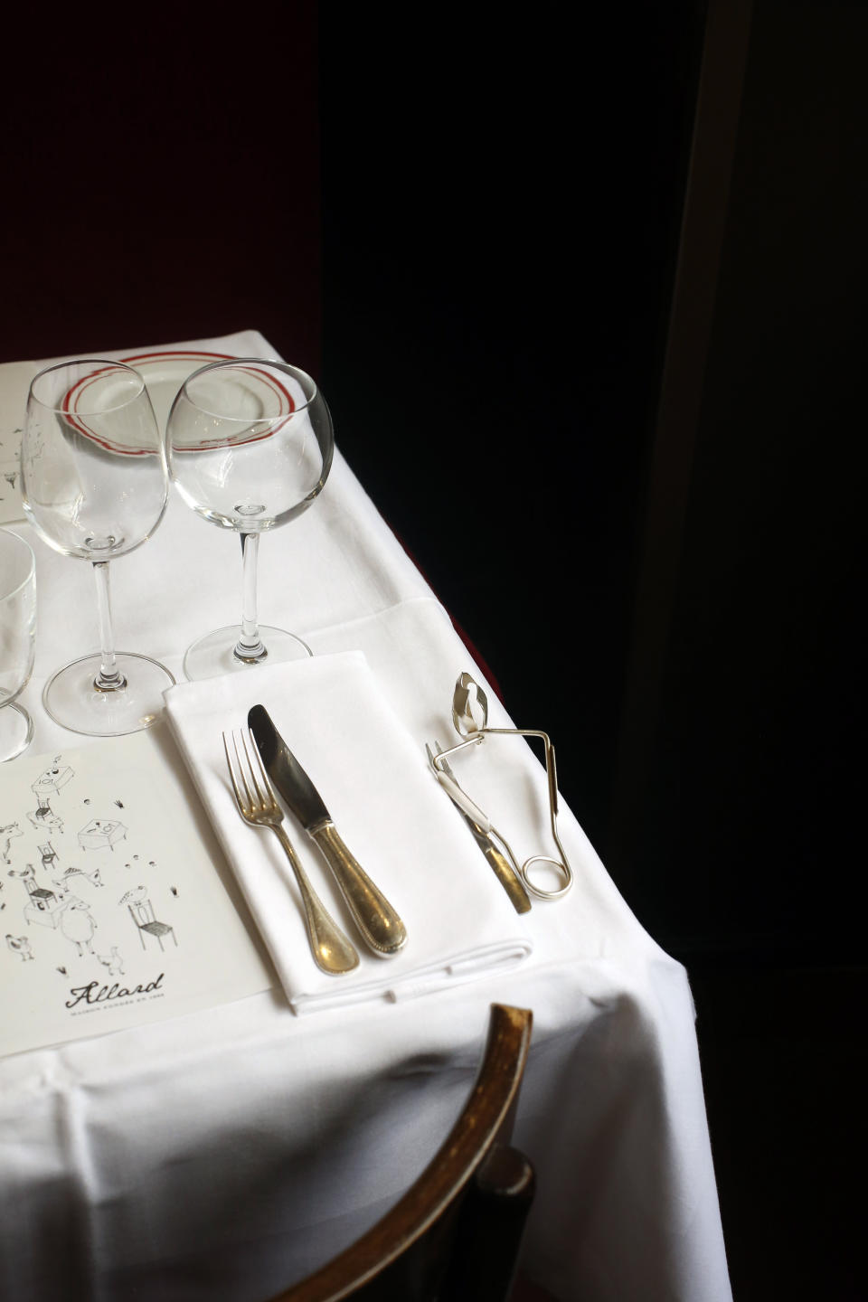 Glasses and cutlery are placed on a table of Alain Ducasse's restaurant « Allard », in Paris, Thursday, June 11, 2020. French Michelin-starred chef Alain Ducasse unveils virus-protection measures as he prepares to reopen his restaurants, including a new filtration system that works to stop virus particles from the air traveling to neighboring tables. (AP Photo/Thibault Camus)