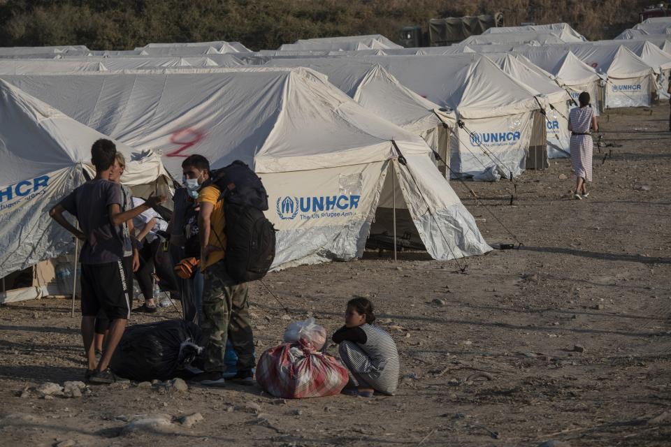 Migrants arrive at a temporary camp near Mytilene town, on the northeastern island of Lesbos, Greece, Saturday, Sept. 12, 2020. Greek authorities have been scrambling to find a way to house more than 12,000 people left in need of emergency shelter on the island after the fires deliberately set on Tuesday and Wednesday night gutted the Moria refugee camp. (AP Photo/Petros Giannakouris)