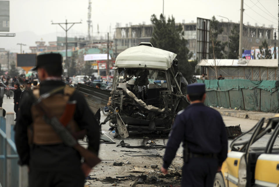 Security personnel inspect the site of a bomb attack in Kabul, Afghanistan, Monday, March 15, 2021. A bomb targeting a minibus in Afghanistan's capital exploded Monday wounding at least 15 civilians, police said, amid a surge in attacks in Kabul. (AP Photo/Rahmat Gul)