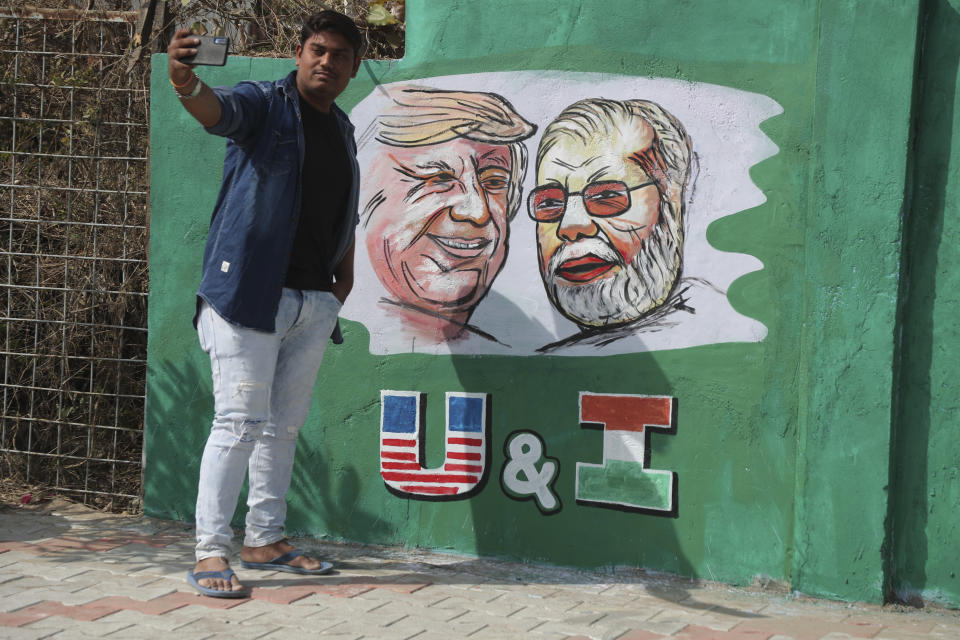 A man takes a selfie with portraits of U.S. President Donald Trump and Indian Prime Minister Narendra Modi painted on a wall ahead of Trump's visit, in Ahmadabad, India, Tuesday, Feb. 18, 2020. Trump is scheduled to visit the city during his Feb. 24-25 India trip. (AP Photo/Ajit Solanki)