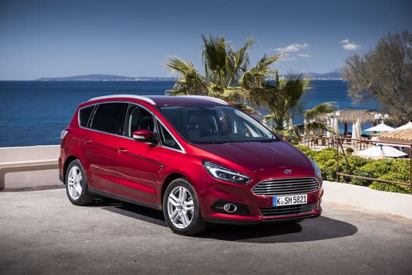 A red Ford S-Max, a tall five-passenger wagon, parked at an upscale beach.