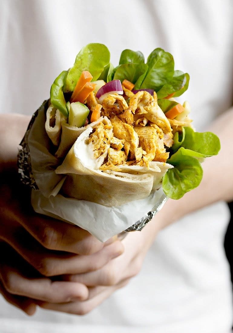 A person holding a Rotisserie Chicken Shawarma Pita Wrap