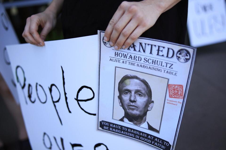 Hannah Crabill holds up a "wanted" poster for CEO Howard Schultz while on strike Monday at the Ricky Drive Starbucks at 11441 San Jose Blvd. Partners at this store made it the first unionized store in Jacksonville when they won their election in May.