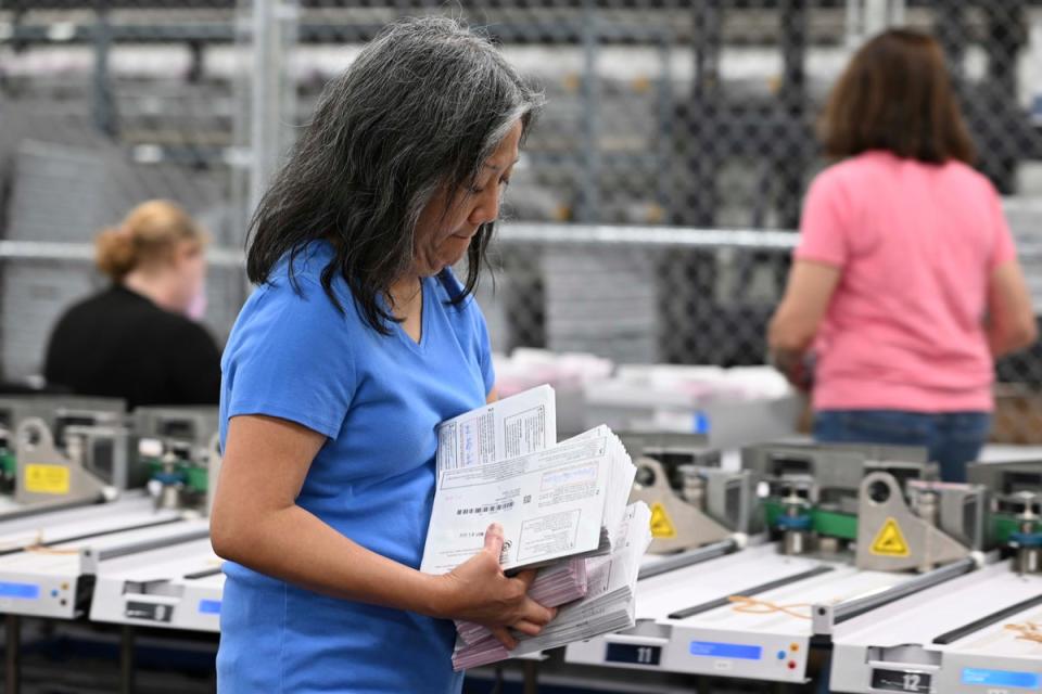 A Washoe County election worker carries stacks of ballots inside a ballot processing room in Reno, Nevada. The state is one of several that Donald Trump’s campaign and Republican Party officials are suing to reject early voting ballots (AP)