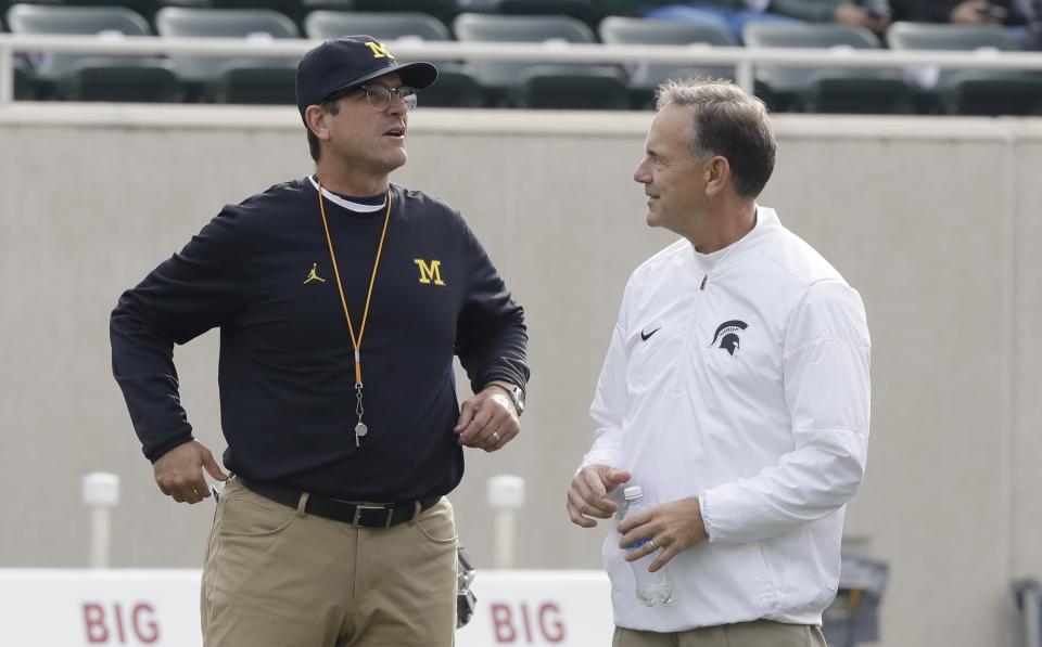 In this Oct. 29, 2016 photo, Michigan head coach Jim Harbaugh (L) greets Michigan State head coach Mark Dantonio before their game in East Lansing, Michigan. (AP Photo/Carlos Osorio, File)