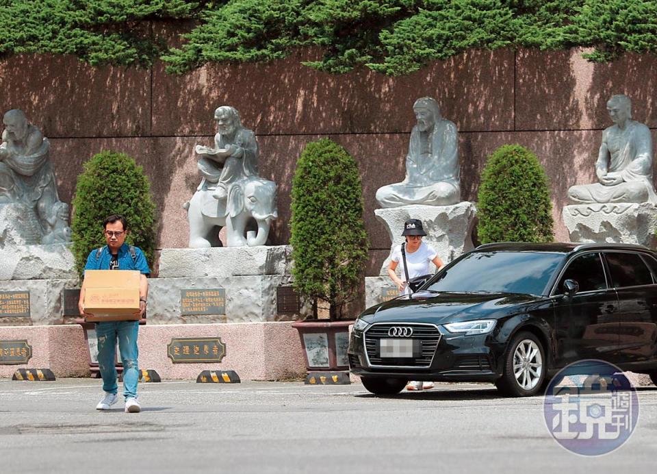 10:06 謝忻的車停在金山的蓬萊陵園，百是傳播製作人先行搬著一箱金紙走在前面，謝忻（右）則戴著漁夫帽下車。