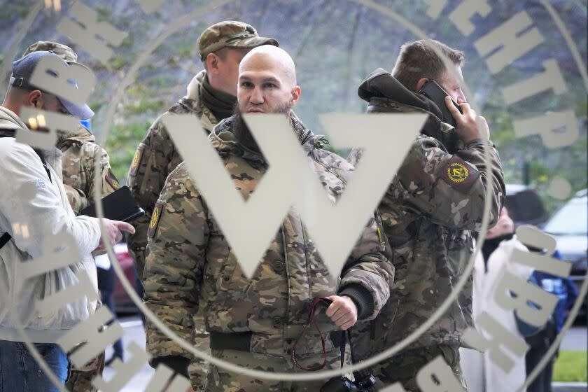 Visitors wearing military camouflage stand at the entrance of the 'PMC Wagner Centre', which is associated with businessman and founder of the Wagner private military group Yevgeny Prigozhin, during the official opening of the office block during National Unity Day, in St. Petersburg, Russia, Friday, Nov. 4, 2022. (AP Photo/Dmitri Lovetsky)