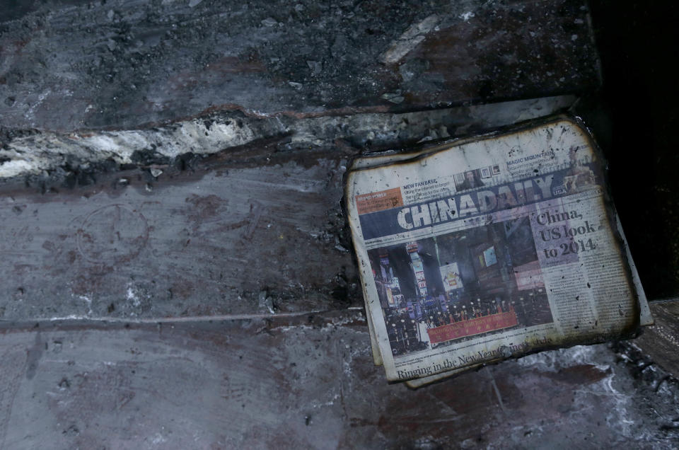 A burned stack of China Daily newspapers sits on a step at the damaged entrance of the Chinese Consulate in San Francisco on Thursday, Jan. 2, 2014. The consulate said in a notice on its website that a person came out of a van parked outside the compound Wednesday night with two buckets of gasoline, poured the fuel on the front of the consulate building and set it on fire. (AP Photo/Jeff Chiu)