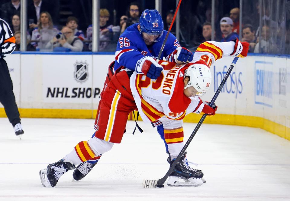 NEW YORK, NEW YORK - FEBRUARY 12: Ryan Lindgren #55 of the New York Rangers checks Andrei Kuzmenko #96 of the Calgary Flames during the second period at Madison Square Garden on February 12, 2024 in New York City.