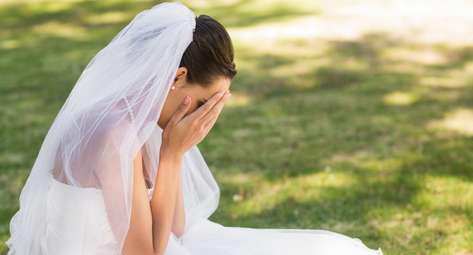 A bride crying on a lawn.