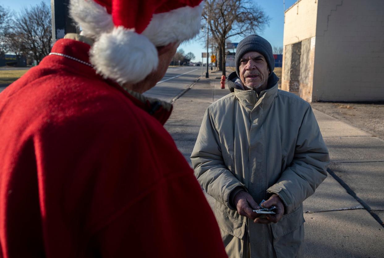 A Secret Santa elf hands two $100 bills to Rod Gawne, 59, during the annual Secret Santa in Lincoln Park on Thursday, Dec. 14, 2023.