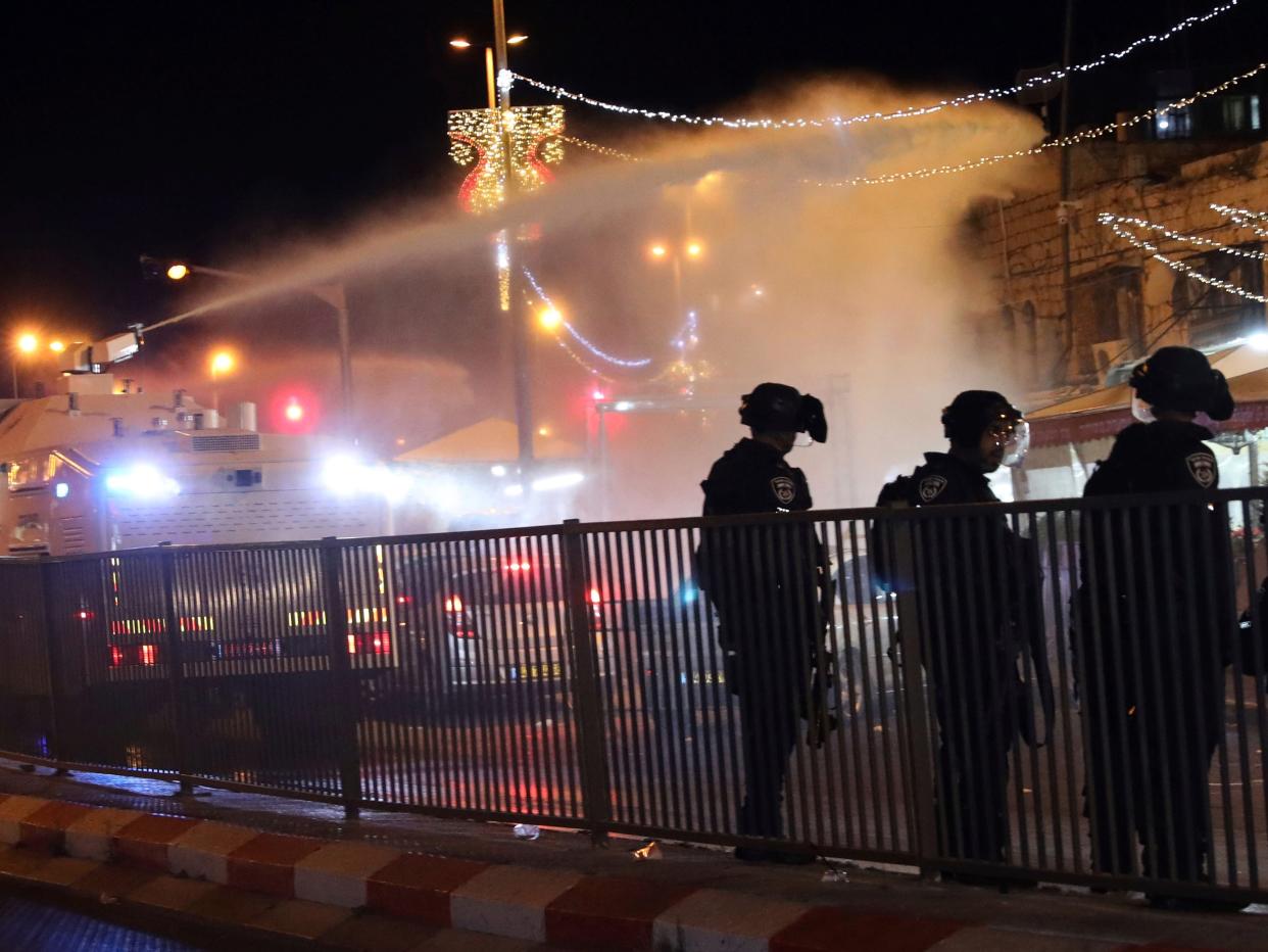 Palestinian women pass through a cordon of Israeli police as they leave the Damascus Gate to the Old City of Jerusalem after clashes at the Al-Aqsa Mosque compound