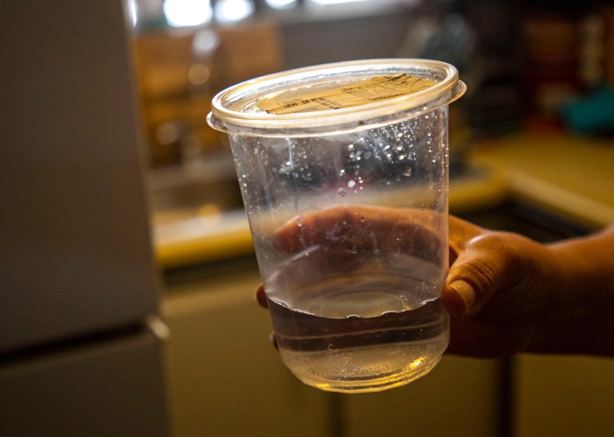 A resident of the Arellano Mobile Home Park shows a container of water from their kitchen sink in Thermal, Calif., Thursday, March 24, 2022.