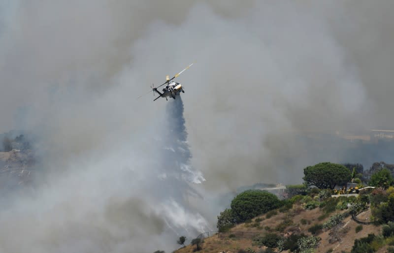 Firefighters battle a blaze from the air that was threatening homes in the Pacific Palisades community of Los Angeles, California