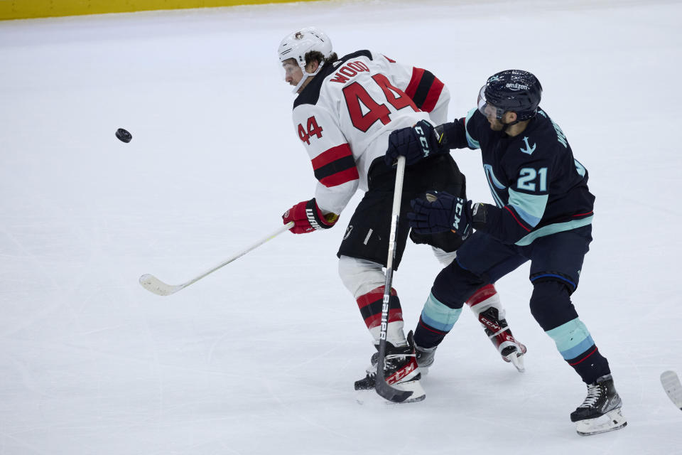 New Jersey Devils left wing Miles Wood (44) battles for the puck with Seattle Kraken center Alex Wennberg (21) during the second period of an NHL hockey game, Thursday, Jan. 19, 2023, in Seattle. (AP Photo/John Froschauer)