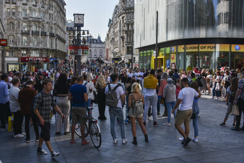 People attend a busking show in Leicester Square, in London, Sunday, Sept. 13, 2020. From Monday, social gatherings of more than six people will be banned in England — both indoors and outdoors — and Boris Johnson hinted that such restrictions will potentially remain in place until or through Christmas. (AP Photo/Alberto Pezzali)