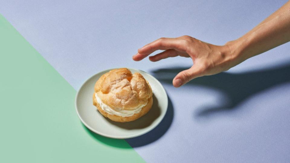 hand reaching out to puff pastry dessert on colorful background