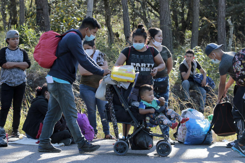 Migrants stand on the side of the road on their way North near Agua Caliente, close to the border with Guatemala, Thursday, Dec. 10, 2020. Honduran security forces stationed on the highway a few kilometers before Agua Caliente, asked the migrants for their passports or identity cards and proof of a COVID-19 test, and if they did not produce those documents they would not be allowed to move on. (AP Photo/Delmer Martinez)