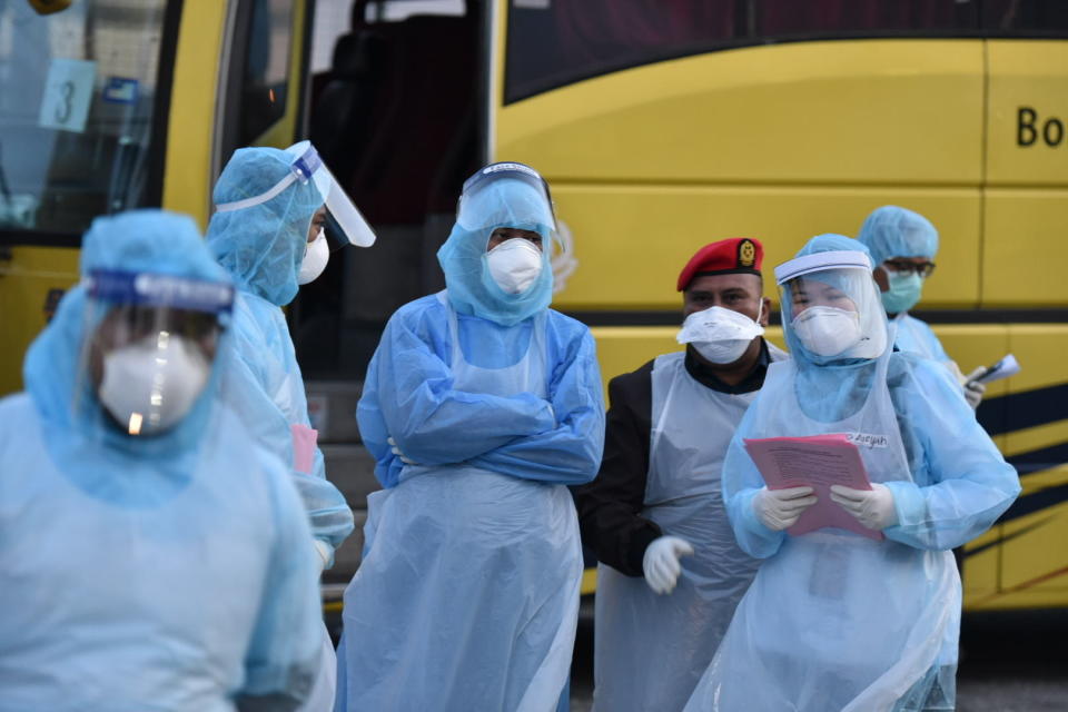 This handout photo taken and released by Malaysia's Ministry of Health shows health officials in protective suits at the Kuala Lumpur International Airport in Sepang, Malaysia, Tuesday, Feb. 4, 2020, waiting for arrivals that were evacuated from China's Wuhan, the epicenter of the novel coronavirus outbreak. (Muzzafar Kasim/Malaysia's Ministry of Health via AP)