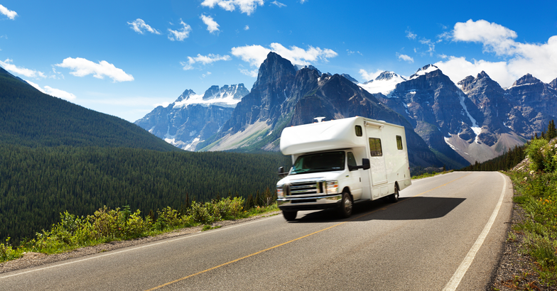 RV on the open road with mountains in the background