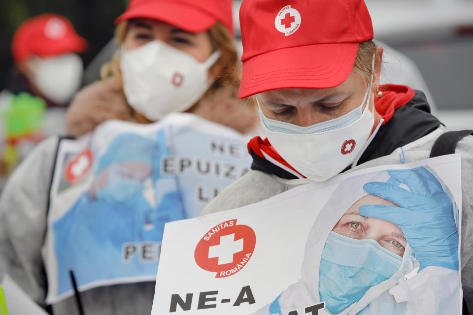 Medical workers, wearing masks for protection against the COVID-19 infection, protest outside the government headquarters demanding payment of the outstanding salaries and the opening of new positions in the national medical system to combat the current staff exhaustion, in Bucharest, Romania, Tuesday, Nov. 3, 2020. Romania registered all time highs for new cases of COVID-19 infection on Tuesday. (AP Photo/Vadim Ghirda)