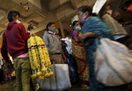 A flower vendor stands with a bunch of garlands for sale as shoppers walk past at a wholesale flower market ahead of the Hindu festival of Dussehra, in Bengaluru, India, Friday, Oct. 23, 2020. Weeks after India fully opened up from a harsh lockdown and began to modestly turn a corner by cutting new infections by near half, a Hindu festival season is raising fears that the disease could spoil the hard-won gains. Health experts worry the festivals can set off a whole new cascade of infections, further testing and straining India’s battered health care system. (AP Photo/Aijaz Rahi)