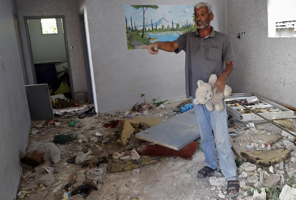 Nasser Abu Fares, who lost three daughters and a grandson when an Israeli artillery bombardment hit his family house during the 11-day war between Israel and Gaza's Hamas rulers in May, holds a teddy bear of one of his daughters, amid the rubble of his house, at the Bedouin village of Umm Al-Nasr, outside the town of Beit Lahia, northern Gaza Strip, Wednesday, Aug. 4, 2021. After initially finding no grounds for disciplinary action, the Israeli military says it is investigating the artillery bombardment that killed six Palestinians, including an infant, in the Gaza Strip last May. (AP Photo/Adel Hana)