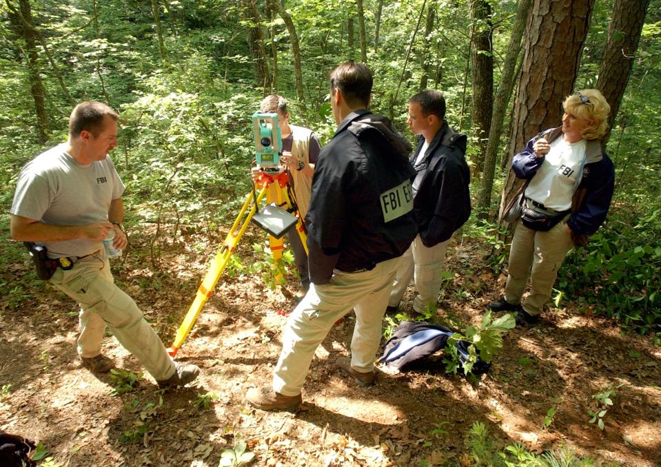 An FBI evidence team surveys a campsite allegedly used by serial bombing suspect Eric Robert Rudolph June 2, 2003 in the woods outside Murphy, North Carolina. Rudolph is a suspect in four bombings, including the 1996 Olympic Park bombing in Atlanta. 