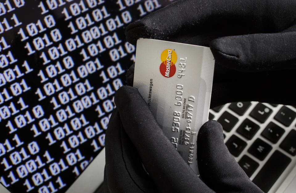 BERLIN, GERMANY - OCTOBER 22: Symbolic feature with topic online crime, data theft and credit card fraudsters, here a close-up of a keyboard of a laptop with hands in black gloves holding a credit card, on October 22, 2013 in Berlin, Germany. (Photo by Thomas Imo/Photothek via Getty Images)