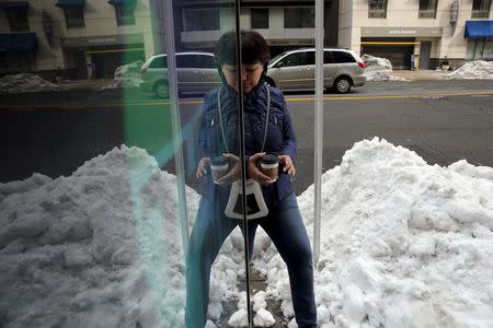 A woman walks carefully around piles of snow at a bus shelter in Washington January 26, 2016. REUTERS/Jonathan Ernst