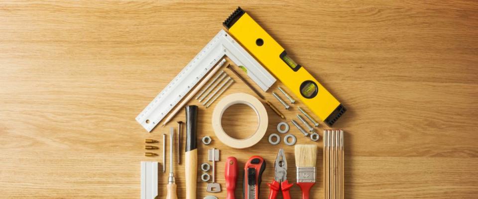 Conceptual house composed of DIY and construction tools on hardwood flooring, top view