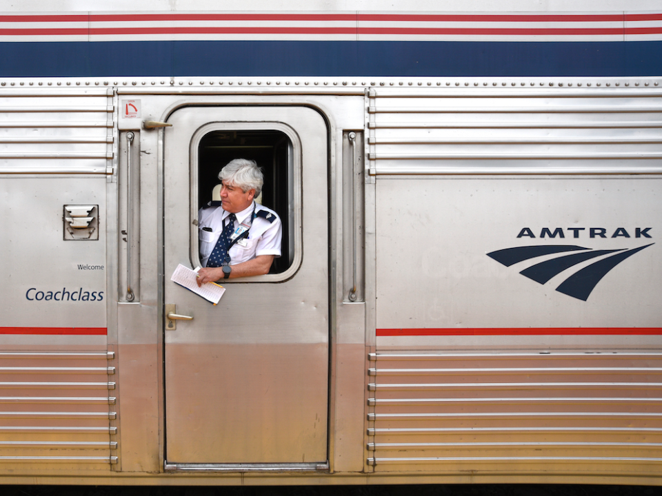 An Amtrak assistant conductor stands at the coach door of a train stopped to pick up and discharge passengers at the railroad station in Lamy, New Mexico, near Santa Fe. Amtrak's Southwest Chief, which transports passengers between Chicago and Los Angeles, makes daily stops at the small Lamy station.